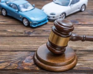 Judge's gavel symbolizing auto insurance and property damage in a road traffic accident involving two cars.