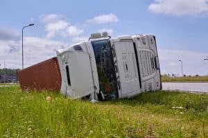 Overturned flatbed truck lying on its side off a roadway, indicating a serious truck accident.