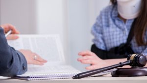 Lawyer discussing documents with a client wearing a neck brace in an office.