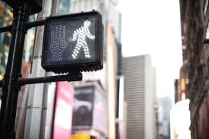 Illuminated pedestrian walk signal at a city intersection, indicating it is safe to cross.