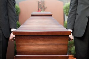 Funeral ceremony with coffin, reflecting on themes of religion, death, and sorrow in a cemetery setting.