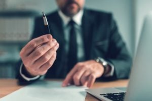 Insurance officer offering a pen to the client for signing an agreement, focus on the pen and hands.